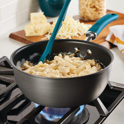 Macaroni cooking in a pot on a stovetop with a spatula.