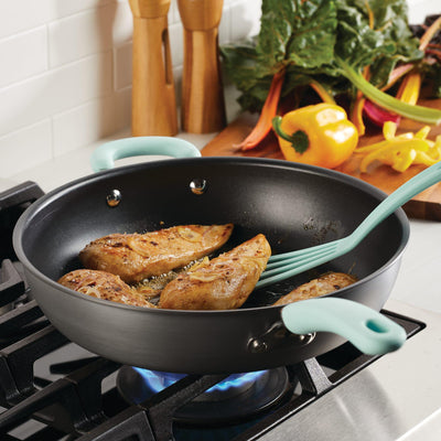 Chicken fillets cooking in a skillet on a stovetop, with vegetables nearby.