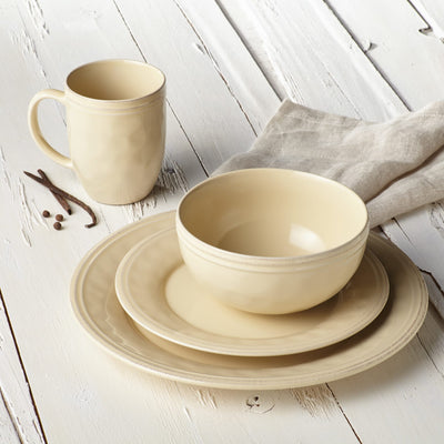 Beige dinnerware set with mug, bowl, and plates on white wooden table.