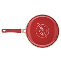 A 3-Quart Cook + Create Nonstick Sauté Pan with Lid in red, featuring a signature on the bottom, a nonstick surface, and a matching red handle.
