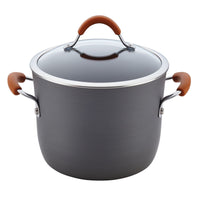 A pot from the 12-Piece Cucina Hard Anodized Nonstick Cookware Set is made from durable aluminum and features a glass lid and brown handles, making it ideal for nonstick cookware enthusiasts.