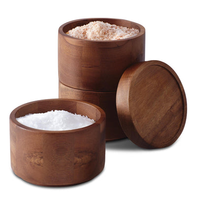 The 3-Tier Stacking Salt Box, crafted from elegant acacia wood and filled with pink and white salt, offers a charming solution for seasoning storage, with one lid resting beside the containers.