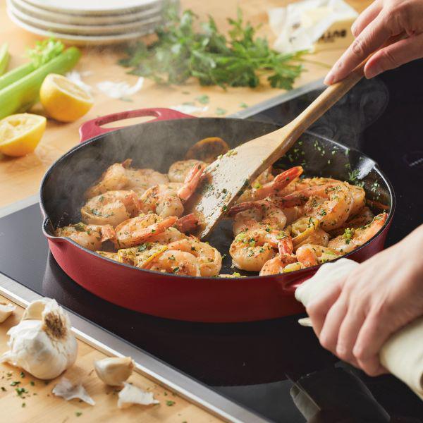 Cooking shrimp with garlic and herbs in the 12-Inch NITRO Cast Iron Skillet on a stovetop.