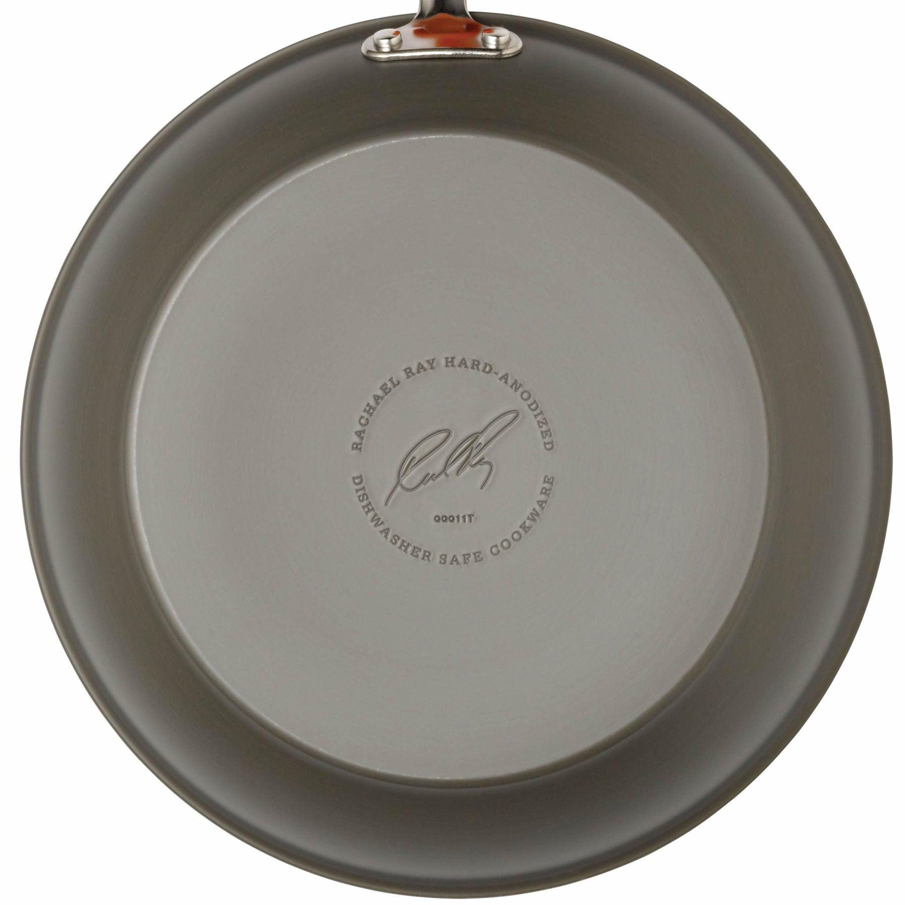 Bottom view of a round, gray pan from the 12-Piece Cucina Hard Anodized Nonstick Cookware Set, crafted from durable aluminum and featuring a label and signature.