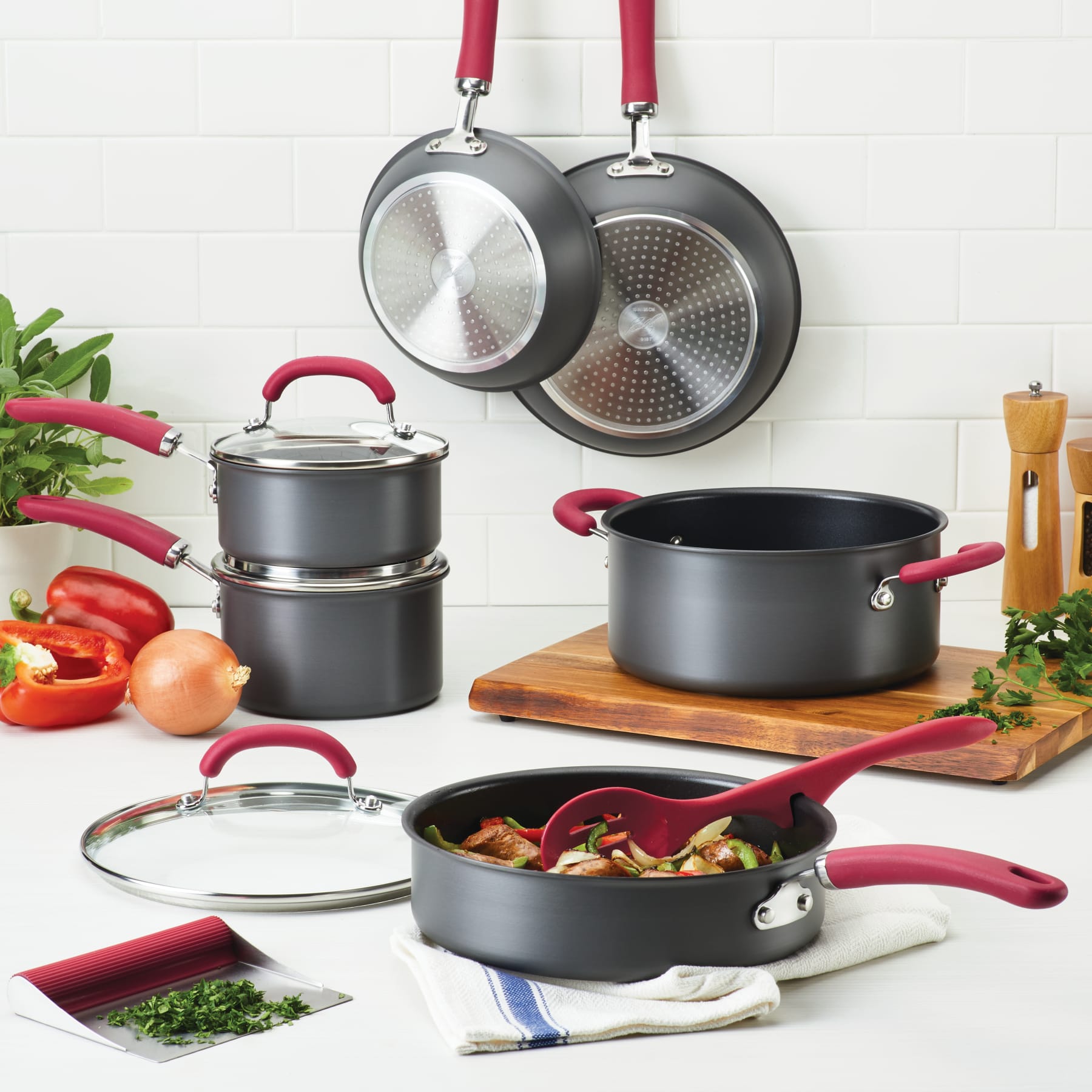 11-piece hard anodized cookware set with red handles, some shown with food.